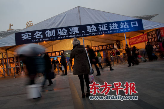昨天，上海火车站南广场，一位旅客站在新搭建的“实名制验票、验证进站口”前。自明年1月1日起，上海地区开行列车均实行火车票实名制。　　早报记者 王炬亮 实习生 杨深来 图